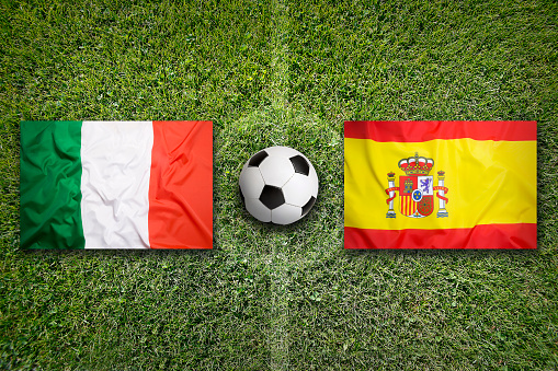 Italy vs. Spain flags on green soccer field