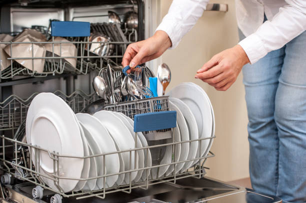 Adult Woman Unloading Dishwasher In The Kitchen stock photo