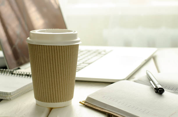 istock Paper cup of coffee on work-table with office stuff, notepad, laptop, pen and coffee cup 644144326
