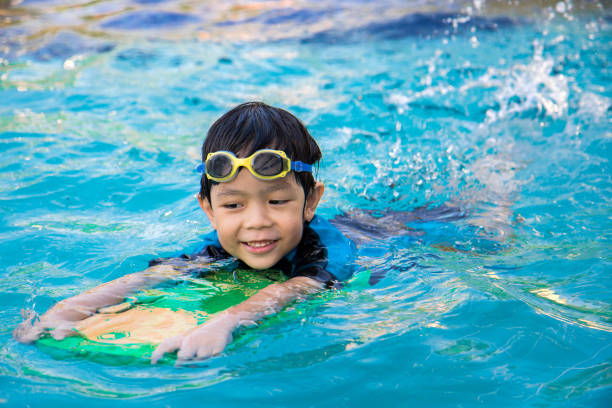 garçon apprennent à nager dans la piscine - color image season people wet photos et images de collection