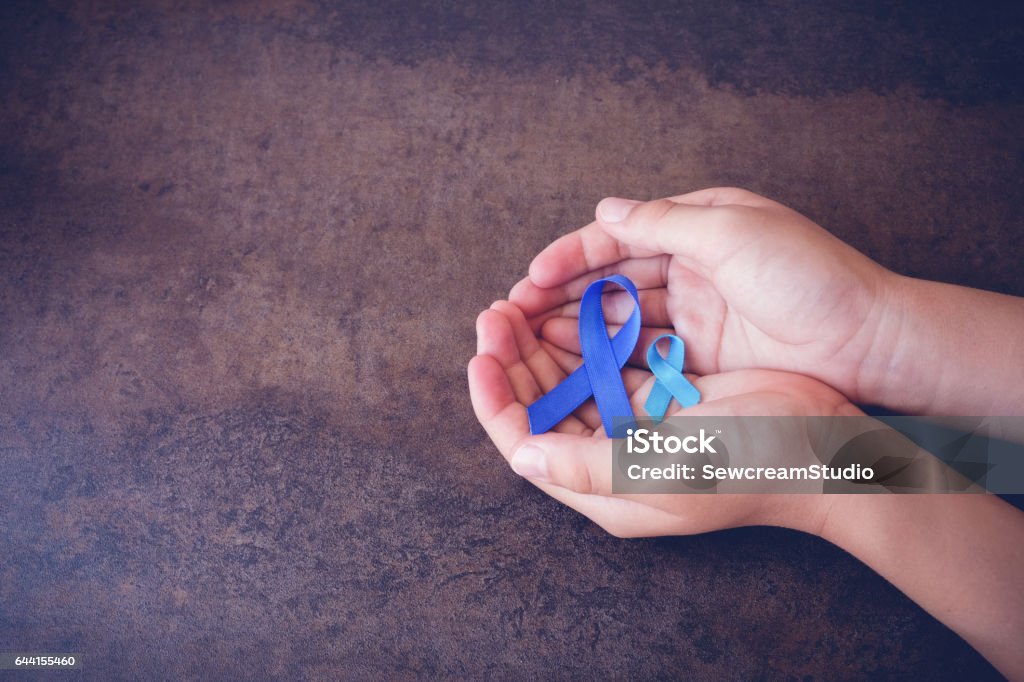 hands holding blue ribbons, toning background Cancer - Illness Stock Photo