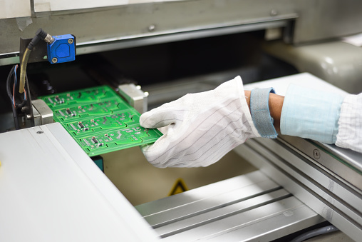 Electrónica fabricación de mano de los trabajadores de fábrica recubierta de engranajes ESD quitar tablero de circuito de impresión desde la línea SMT photo