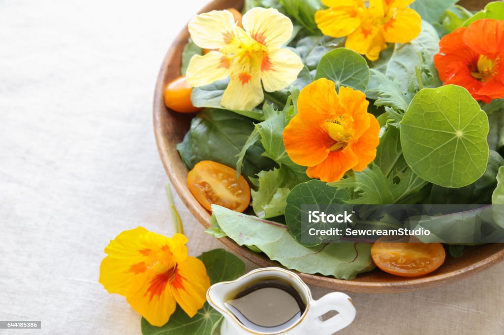 Fresh green salad with edible flowers nasturtium in wooden serving dish Nasturtium Stock Photo