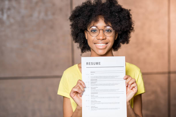 African woman with resume Portrait of a young african woman holding resume document indoors good cv stock pictures, royalty-free photos & images