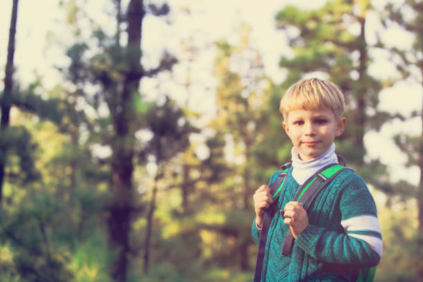 istock happy little boy with backpack travel in green forest 644191350