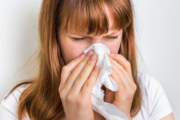 istock Woman with allergy or flu cold symptoms sneezing in tissue 644210468