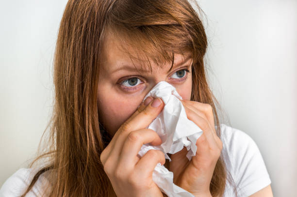 istock Woman with allergy or flu cold symptoms sneezing in tissue 644210658