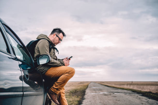 Man using smart phone Man sitting on the car and using smart phone vehicle breakdown stock pictures, royalty-free photos & images