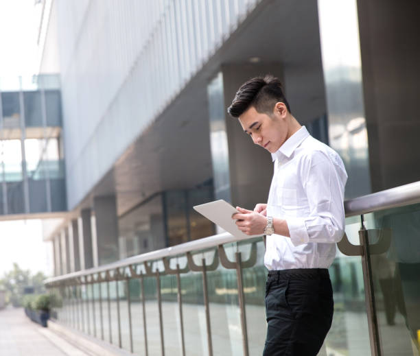 young asian businessman using tablet at office exterior stock photo