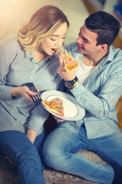 istock Couple relaxing at home and eating pizza 644255604
