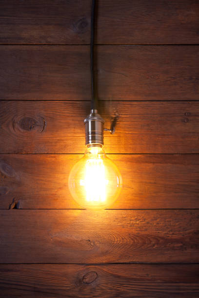 istock Vintage incandescent Edison type bulb on old wooden table 644282398