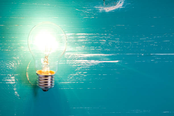istock Vintage incandescent bulb on turquoise wooden table 644283852