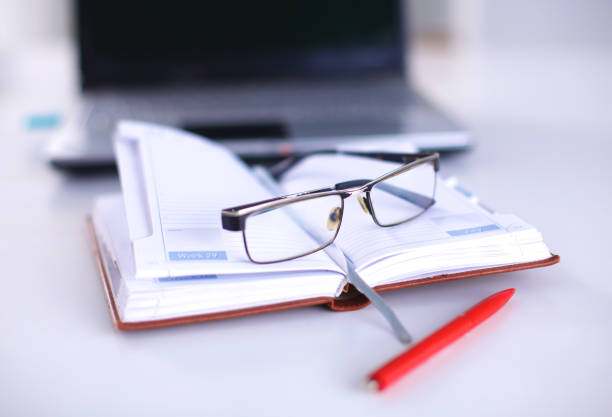 istock A note book, laptop, pen, graph paper document on the office desk table behind white blind 644298936
