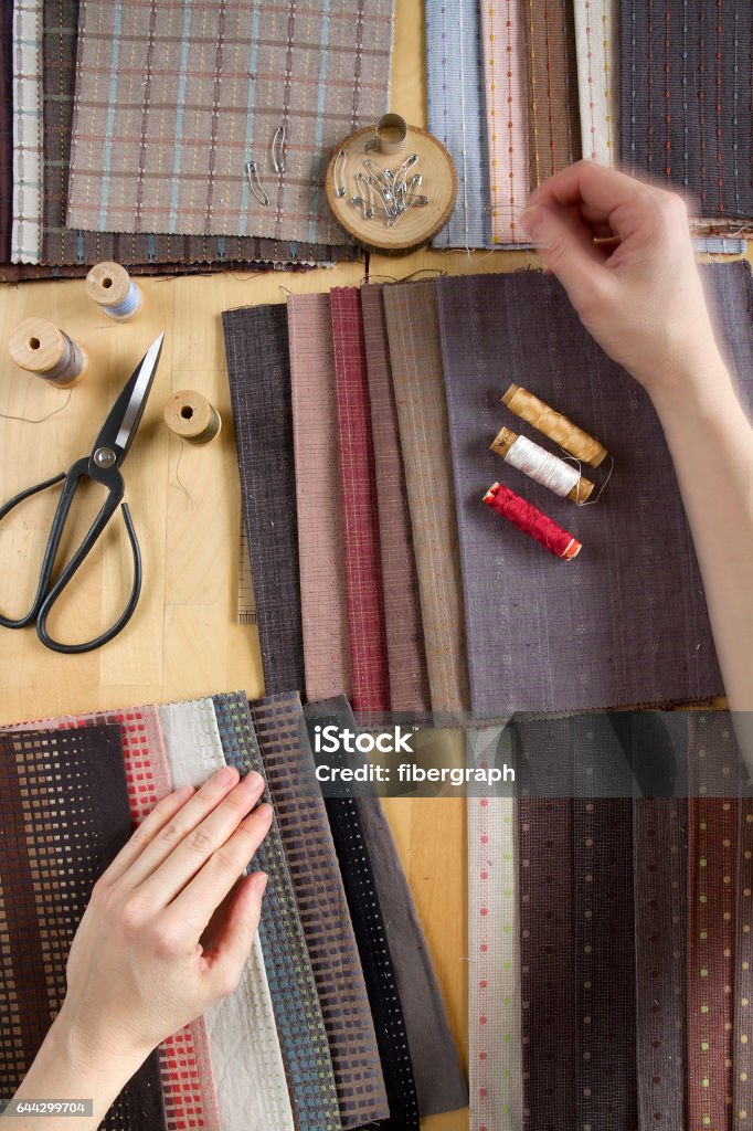 Вид сверху швейного стола с тканями, принадлежностей для домашнего декора или стеганого проекта и женской руки - Стоковые фото В помещении роялти-фри