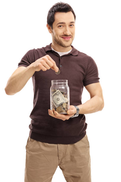 Young man putting a coin into jar with money