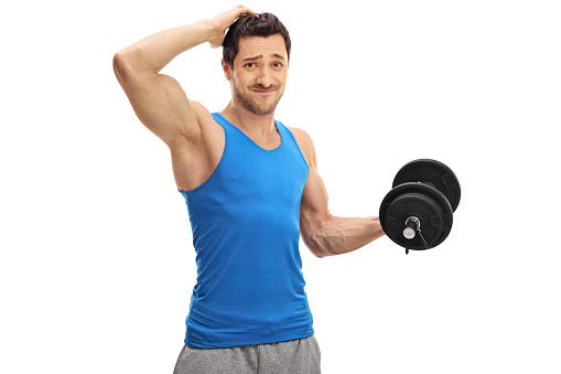 Tired guy lifting a dumbbell and holding his head isolated on white background