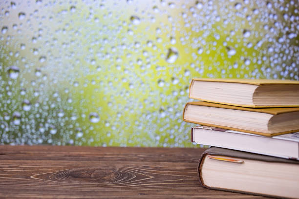 Books on an retro wooden table on a rainy day window background. Autumn. Study concept
