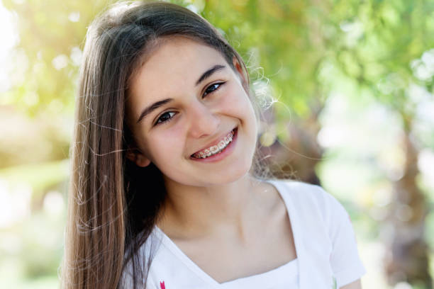 Pretty teenage girl wearing braces smiling cheerfully Beautiful teenage girl smiling with braces outdoors happy young teens stock pictures, royalty-free photos & images