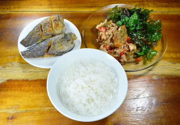 boiled rice eat with stir fried crispy basil leaf with black preserved egg and deep fried fish