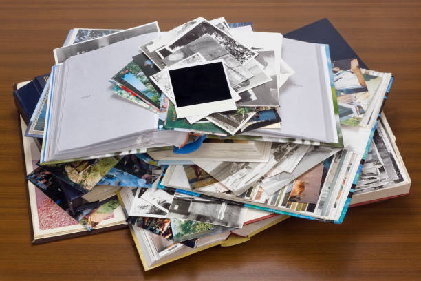 Nostalgia by youth - old family photo albums and photos lie a heap on a wooden table. stock photo