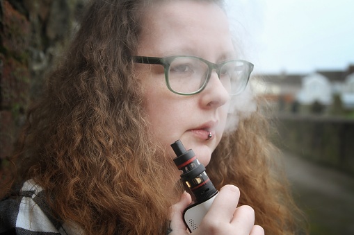 young woman smoking electronic cigarette, vaping