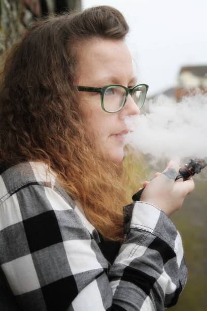 istock young woman smoking electronic cigarette, vaping 644354912