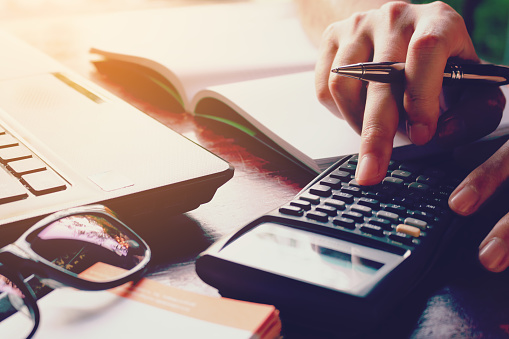 Close up woman doing finance at home office with calculate expenses.