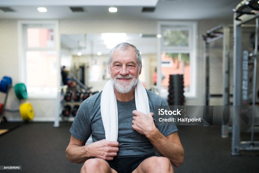 Fit senior man in gym working his abs, doing crunches. Fit senior man in gym in sports clothing working his abs, doing abdominal crunches. Gym Stock Photo