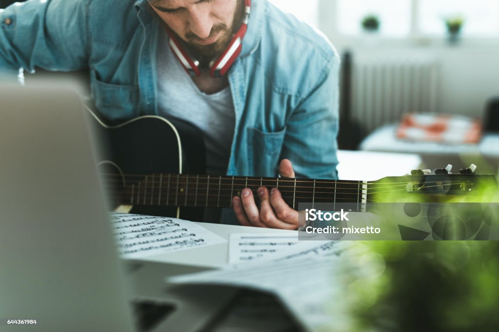 Learning to play guitar Photo of young man playing guitar at home 25-29 Years Stock Photo