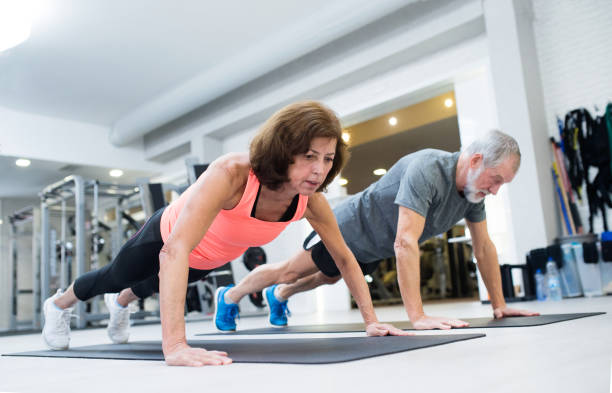 Senior couple in gym working out, doing push ups Beautiful fit senior couple in gym working out, doing push ups. push ups stock pictures, royalty-free photos & images