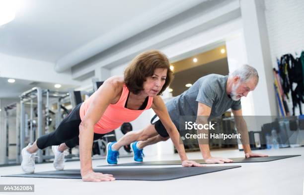 Senior Couple In Gym Working Out Doing Push Ups Stock Photo - Download Image Now - Push-ups, Senior Adult, Exercising