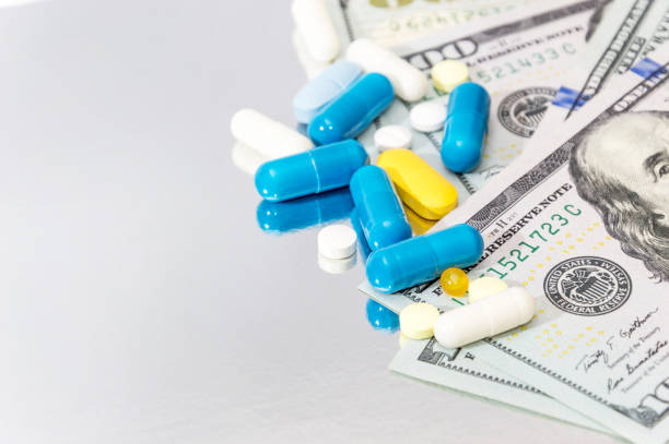 istock Pills with money on reflective background. 644371744
