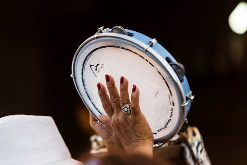 Conservatoria (Rio de Janeiro), Brazil - July 09, 2013: Woman playing tambourine during a performance of Mulheres de Aquilah (portuguese for Women of Aquilah) samba group presentation on the streets of historic viallage. The group is formed exclusively by women percussionists and is based in Madureira, popular samba neighborhood in Rio de Janeiro capital.