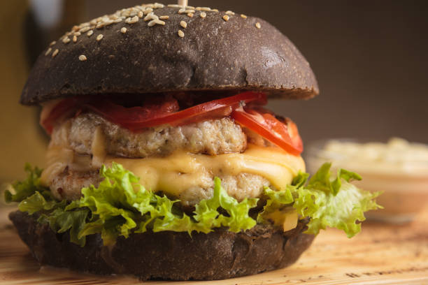 istock Trendy burger with chicken in black bun 644432250