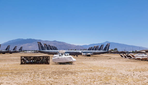 Side view of a passenger airplane aligned on the runway, preparing for takeoff with mountains in the distance.