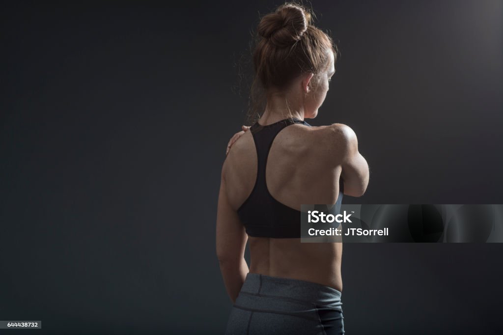 Woman Holding Her Shoulder An athletic woman holding her shoulder (seen from behind) 20-29 Years Stock Photo