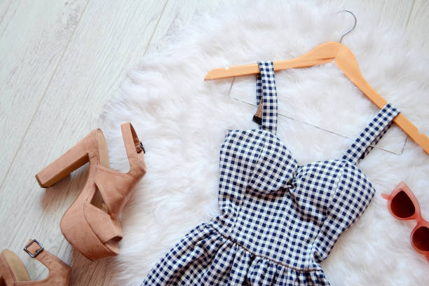 Fashion concept. Summer dress in a cage, beige shoes and rose-colored glasses. top view Fashion concept. Summer dress in a cage, beige shoes and rose-colored glasses. top view sundress stock pictures, royalty-free photos & images