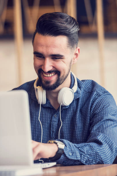 istock Cheerful Young Man Using Tablet with Earphones In Coffee Shop 644513108