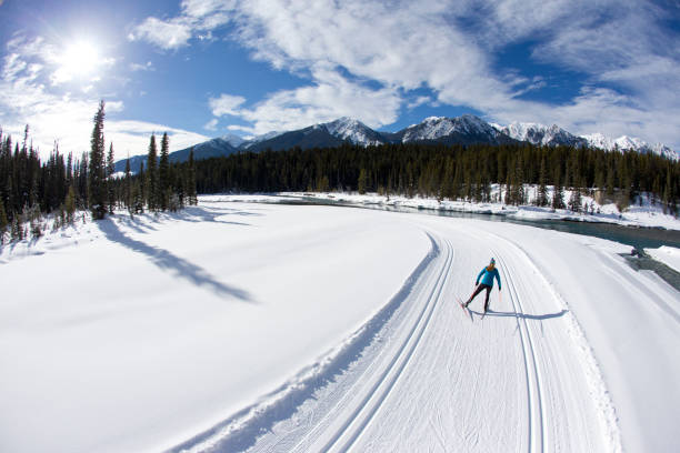 una mujer disfruta de una estación de esquí a campo través skate junto a un río en las montañas rocosas de canadá. - back country skiing fotos fotografías e imágenes de stock