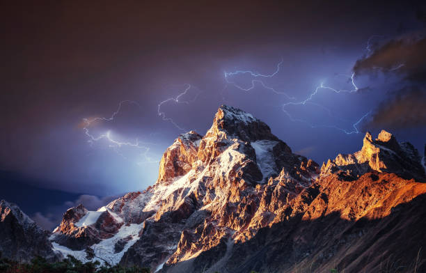 fantastyczny kolaż. piękna błyskawica nad ośnieżonym - snow capped mountain peaks zdjęcia i obrazy z banku zdjęć