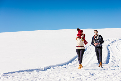 Couple having fun running down slope on winter at mountain.