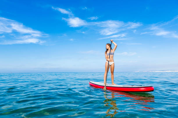 woman practicing paddle - women paddleboard bikini surfing imagens e fotografias de stock