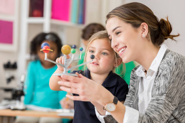 istock Confident teacher talks with young student about the planets 644681878
