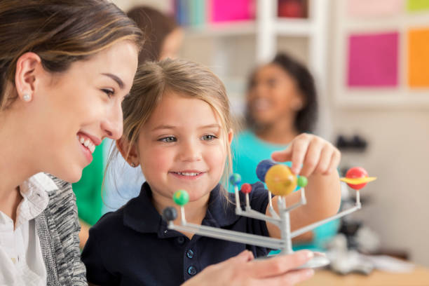 istock Beautiful Caucasian elementary teacher talks about astronomy with young student 644681894