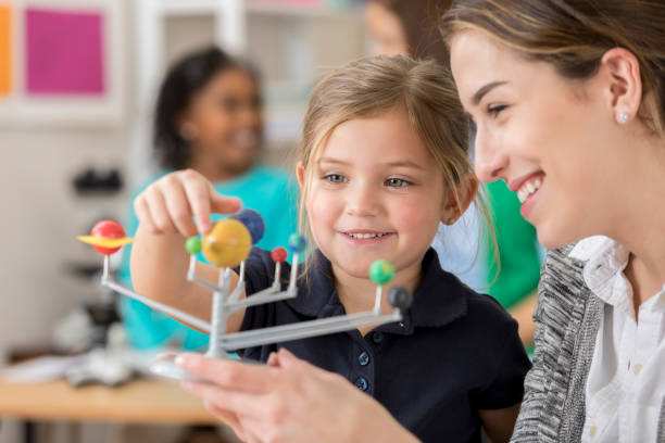 istock Happy elementary school teacher and student in astronomy class 644681950