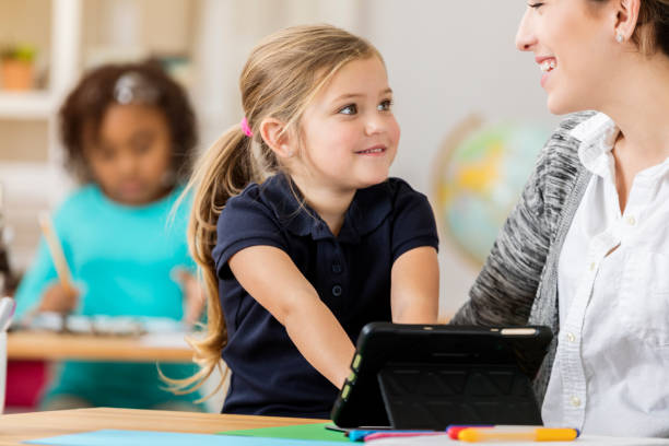 istock Happy schoolgirl talks with teacher at school 644682146