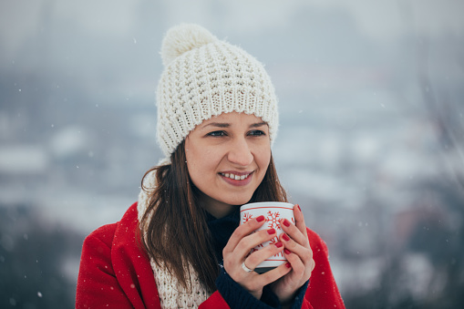 One woman, winter day, relaxing outdoors, holding tea cup.
