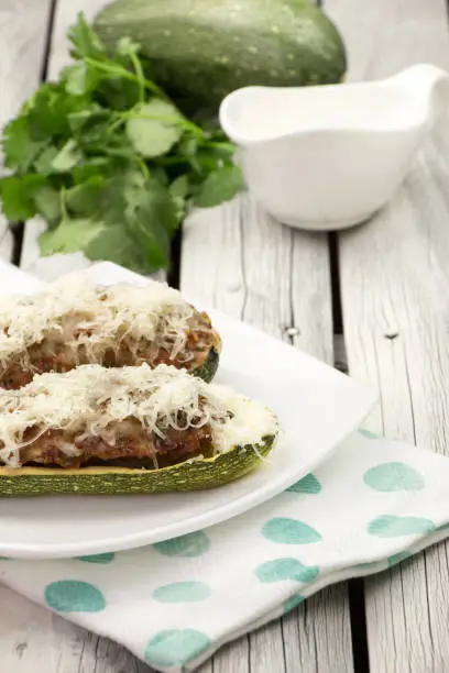 Stuffed zucchini with ground turkey and cilantro on the white plate. Spring menu. Green squash. Healthy lifestyle. Green veggies. Easter dinner.