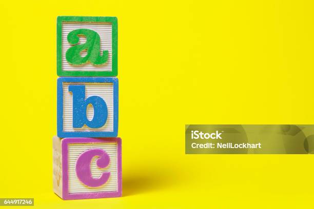 Abc Alphabet Blocks Stacked Up On Yellow Background Stock Photo - Download Image Now