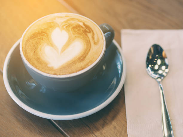 istock Cappuccino coffee in black cup on wooden table. 644926312